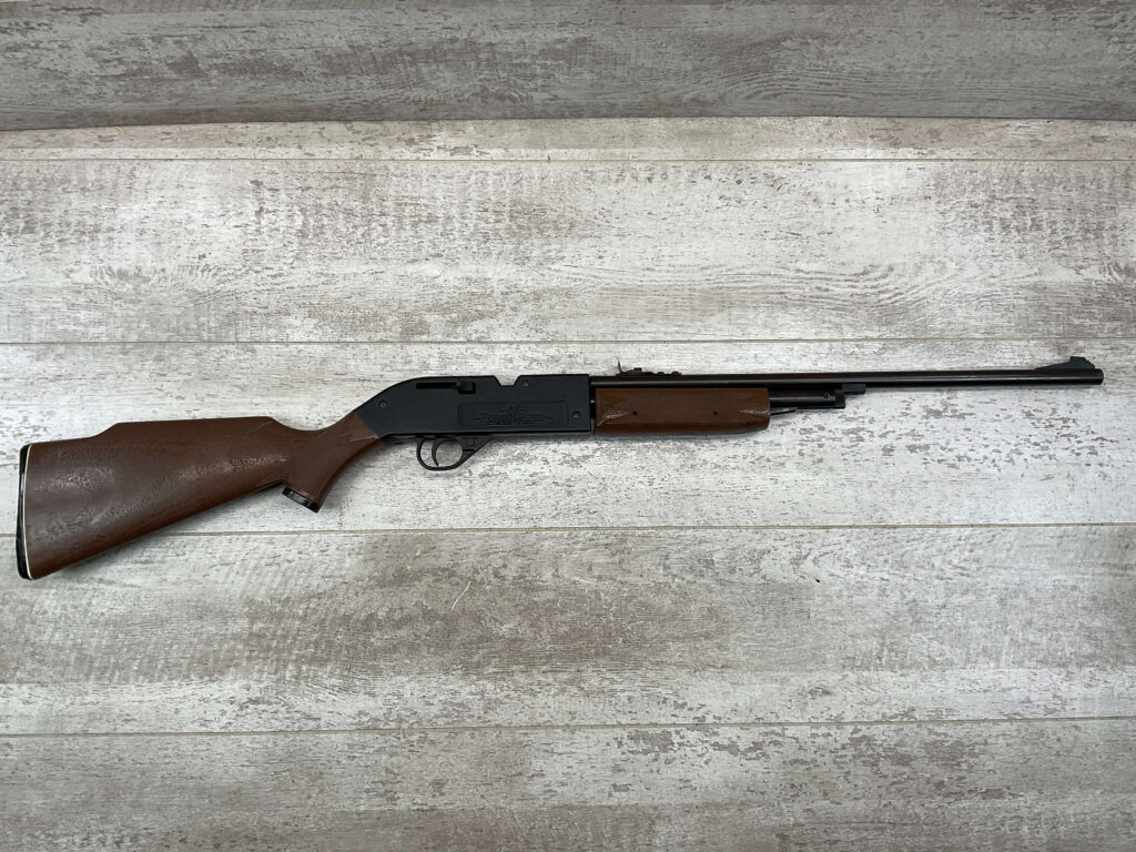 Firearm replica of a rifle or shotgun laying on a wooden surface, used for display or decoration at Checkpoint Charlie's, a famous Berlin historical site and tourist attraction.