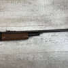 Air rifle with wooden stock, used for shooting practice or sport, placed on a wooden surfaceâ€”highlighting outdoor activity or hunting gear at Checkpoint Charlie's.