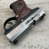 9mm handgun with stainless steel slide and wooden grip, displayed on wooden surface, associated with firearm collection and shooting sports.