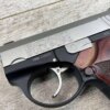 9mm handgun with "BOND BULLPUP 9" engraved, featuring a stainless steel slide and wooden grip, positioned on a wooden surface.
